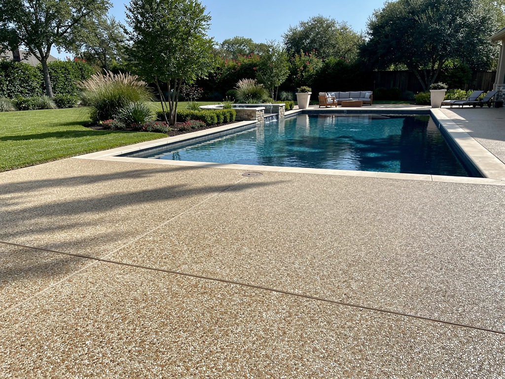 Exposed aggregate concrete patio with pea gravel finish around a pool in Magnolia, TX